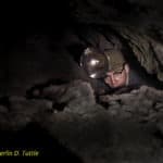 Merlin Tuttle in 1960 emerging from tight crawlway passage in Pearson Cave, Tennessee while searching for gray bats.