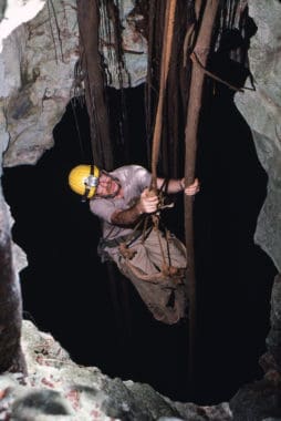 Merlin Tuttle and his photo equipment  being lowered some 60 feet into a Jamaican cave in a guano collecting bag in 1985. The goal was to photograph male Jamaican fruit-eating bats guarding their harems. The men insisted on Merlin holding onto a vine in case the rope broke!